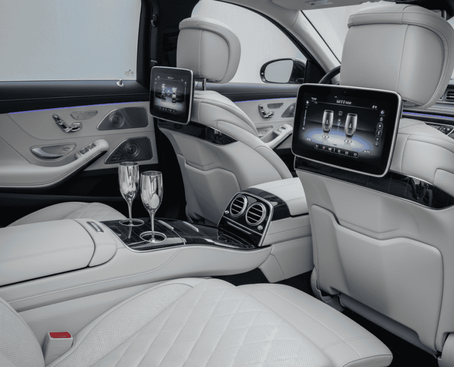 Luxurious rear cabin of the Mercedes-Maybach S-Class with reclining seats, entertainment screens, and champagne flutes