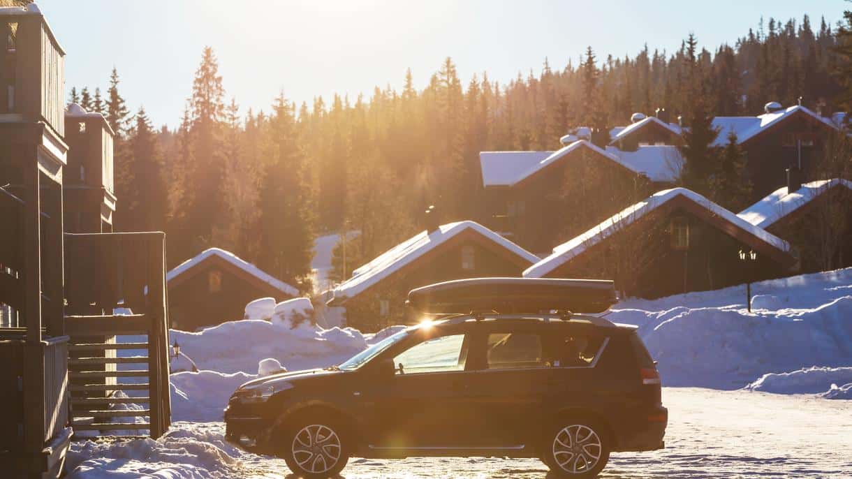 SUV with a ski rack driving on a snowy mountain road, illustrating the need for AWD when traveling to Hunter or Windham