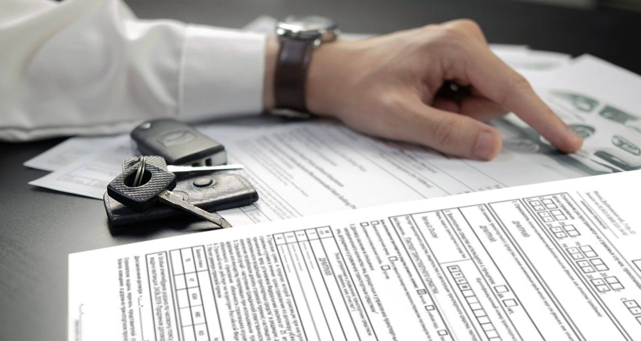 Car rental documents, car keys and a hand checking the documents